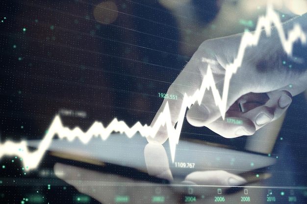 Doble exposición de las manos del hombre sosteniendo y usando un dispositivo digital y un gráfico de forex Concepto de mercado financiero