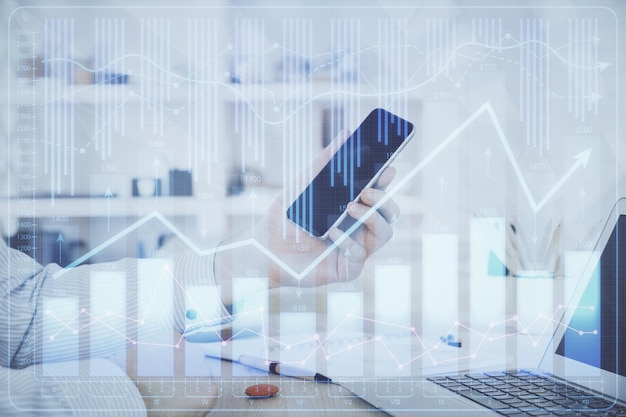 Doble exposición de las manos del hombre sosteniendo y utilizando un dispositivo digital y dibujo de gráficos de divisas Concepto de mercado financiero