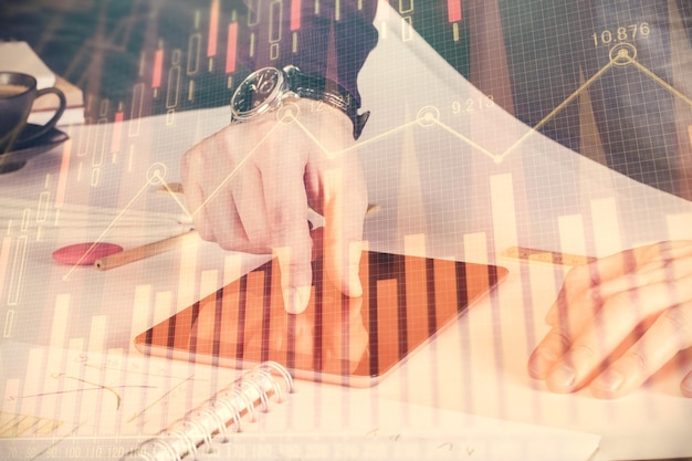 Doble exposición de las manos del hombre sosteniendo y utilizando un dispositivo digital y dibujo de gráficos de divisas Concepto de mercado financiero