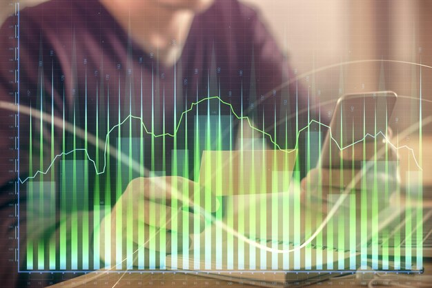 Doble exposición de las manos de los hombres sosteniendo y usando un teléfono y dibujando gráficos financieros Concepto de análisis