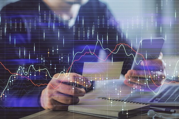 Doble exposición de las manos de los hombres sosteniendo y usando un teléfono y dibujando gráficos financieros Concepto de análisis