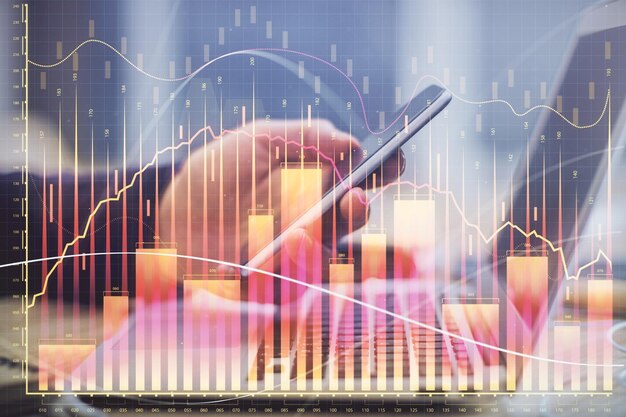 Doble exposición de las manos de los hombres sosteniendo y usando un teléfono y dibujando gráficos financieros Concepto de análisis