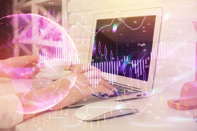 Doble exposición de las manos de la mujer escribiendo en la computadora y dibujo de hologramas de gráficos de divisas Concepto de análisis del mercado de valores