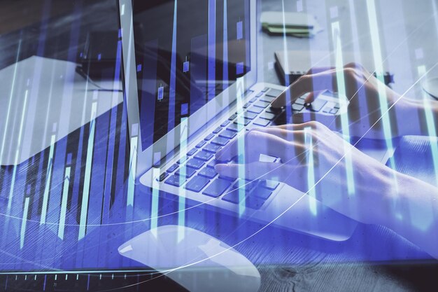 Doble exposición de las manos de la mujer escribiendo en la computadora y dibujo de hologramas de gráficos de divisas Concepto de inversión en el mercado de valores