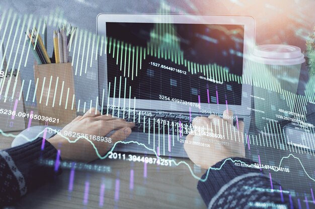 Doble exposición de las manos de la mujer escribiendo en la computadora y dibujo de hologramas de gráficos de divisas Concepto de inversión en el mercado de valores