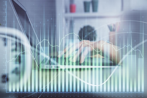 Doble exposición de las manos de la mujer escribiendo en la computadora y dibujo de hologramas de gráficos de divisas Concepto de inversión en el mercado de valores