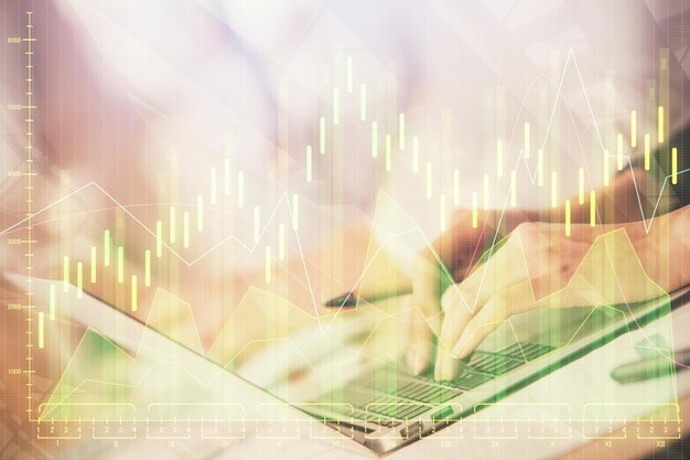 Doble exposición de las manos de la mujer escribiendo en la computadora y dibujo de hologramas de gráficos de divisas Concepto de inversión en el mercado de valores