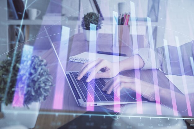 Doble exposición de las manos de la mujer escribiendo en la computadora y dibujo de hologramas de gráficos de divisas Concepto de inversión en el mercado de valores
