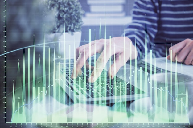 Doble exposición de las manos de la mujer escribiendo en la computadora y dibujo de hologramas de gráficos de divisas Concepto de inversión en el mercado de valores