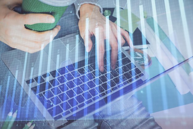 Doble exposición de las manos de la mujer escribiendo en la computadora y dibujo de hologramas de gráficos de divisas Concepto de inversión en el mercado de valores