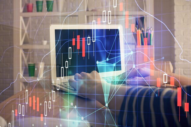 Doble exposición de las manos de la mujer escribiendo en la computadora y dibujo de hologramas de gráficos de divisas Concepto de inversión en el mercado de valores