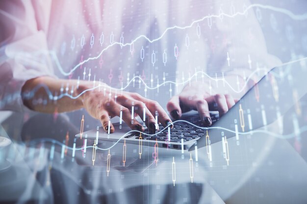 Doble exposición de las manos de la mujer escribiendo en la computadora y dibujo de hologramas de gráficos de divisas Concepto de inversión en el mercado de valores