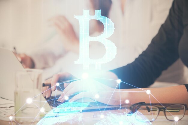 Doble exposición de manos de mujer escribiendo en computadora y holograma de tema de mercado criptográfico dibujando el concepto Blockchain