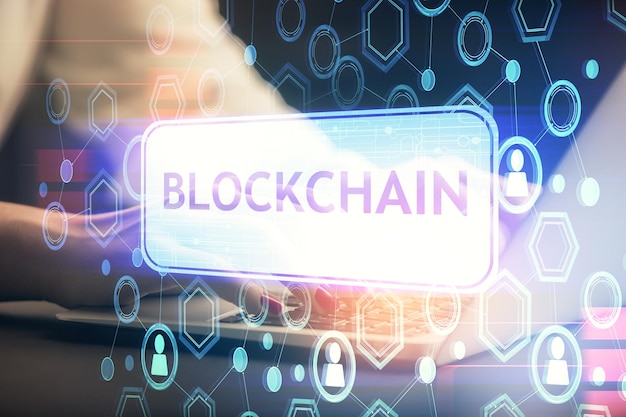 Doble exposición de manos de mujer escribiendo en computadora y holograma de tema de mercado criptográfico dibujando el concepto Blockchain