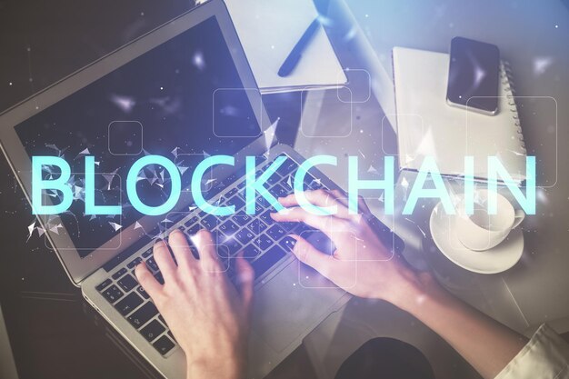Doble exposición de manos de mujer escribiendo en computadora y holograma de tema de mercado criptográfico dibujando el concepto Blockchain
