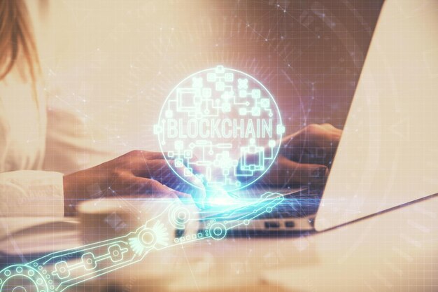 Doble exposición de manos de mujer escribiendo en computadora y holograma de tema de mercado criptográfico dibujando el concepto Blockchain