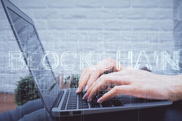 Doble exposición de manos de mujer escribiendo en computadora y holograma de tema de mercado criptográfico dibujando el concepto Blockchain