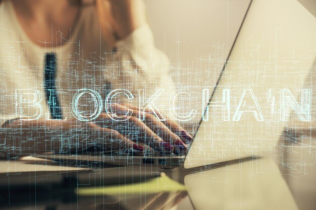 Doble exposición de manos de mujer escribiendo en computadora y holograma de tema de mercado criptográfico dibujando el concepto Blockchain