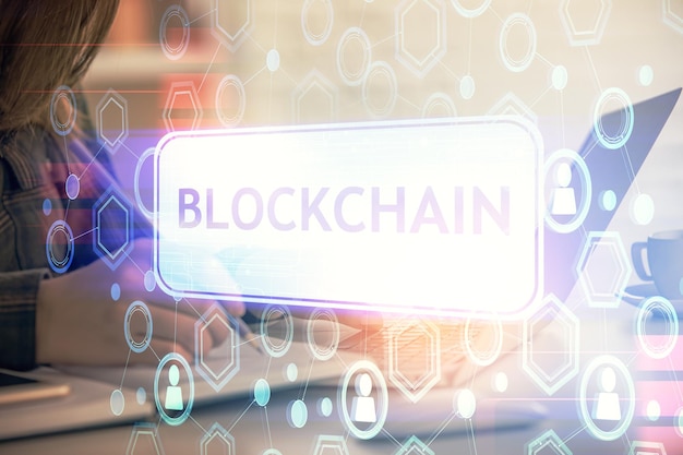 Doble exposición de manos de mujer escribiendo en computadora y holograma de tema de mercado criptográfico dibujando el concepto Blockchain