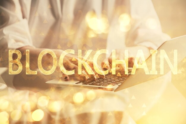 Doble exposición de manos de mujer escribiendo en computadora y holograma de tema de mercado criptográfico dibujando el concepto Blockchain