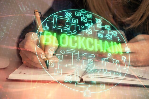 Doble exposición de manos de mujer escribiendo en computadora y holograma de tema de mercado criptográfico dibujando el concepto Blockchain