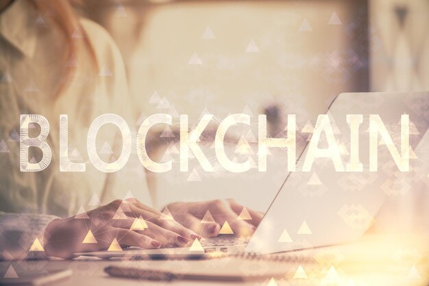 Doble exposición de manos de mujer escribiendo en computadora y holograma de tema de mercado criptográfico dibujando el concepto Blockchain