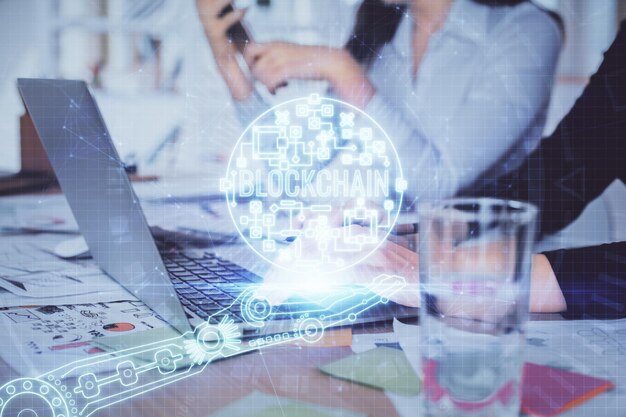 Doble exposición de manos de mujer escribiendo en computadora y holograma de tema de mercado criptográfico dibujando el concepto Blockchain
