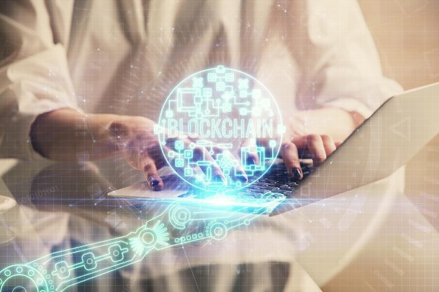 Doble exposición de manos de mujer escribiendo en computadora y holograma de tema de mercado criptográfico dibujando el concepto Blockchain