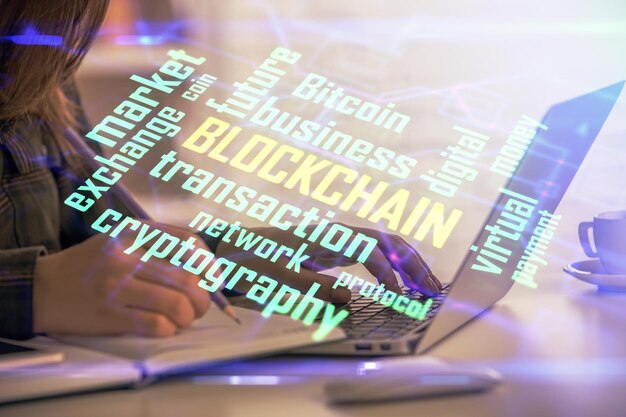 Doble exposición de manos de mujer escribiendo en computadora y holograma de tema de mercado criptográfico dibujando el concepto Blockchain