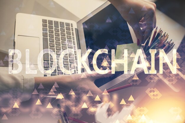 Doble exposición de manos de mujer escribiendo en computadora y holograma de tema de mercado criptográfico dibujando el concepto Blockchain