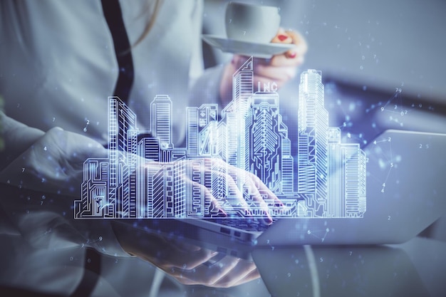 Doble exposición de manos de mujer escribiendo en computadoras y edificios dibujando el concepto Smartcity