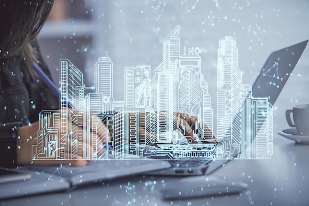 Doble exposición de manos de mujer escribiendo en computadoras y edificios dibujando el concepto Smartcity