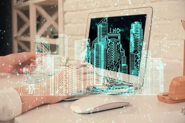 Doble exposición de manos de mujer escribiendo en computadoras y edificios dibujando el concepto Smartcity