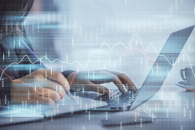 Doble exposición de las manos de una mujer de negocios escribiendo en la computadora y dibujando un holograma de gráficos de divisas Concepto de análisis financiero
