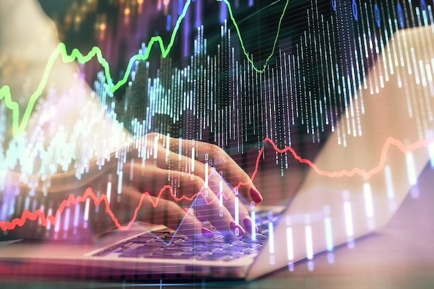 Doble exposición de las manos de una mujer de negocios escribiendo en la computadora y dibujando un holograma de gráficos de divisas Concepto de análisis financiero