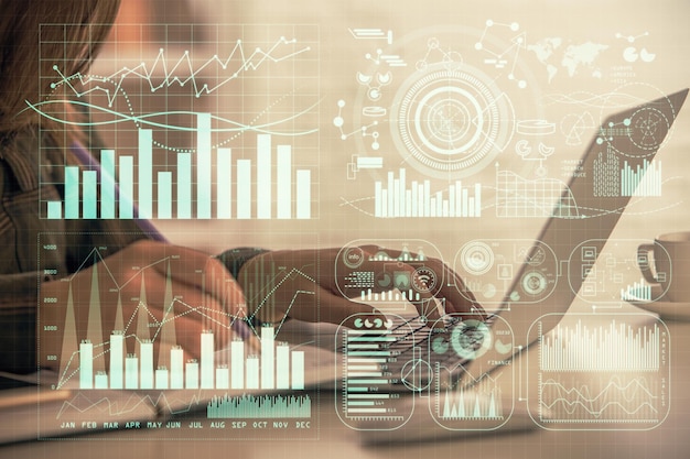 Doble exposición de las manos de una mujer de negocios escribiendo en la computadora y dibujando un holograma de gráficos de divisas Concepto de análisis financiero