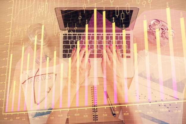 Doble exposición de manos de mujer trabajando en computadora y gráfico de forex holograma dibujo Vista superior Concepto de análisis financiero