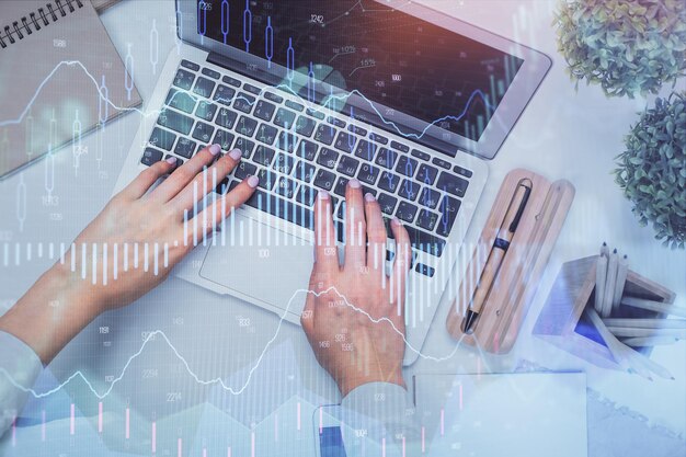 Doble exposición de manos de mujer trabajando en computadora y gráfico de forex holograma dibujo Vista superior Concepto de análisis financiero
