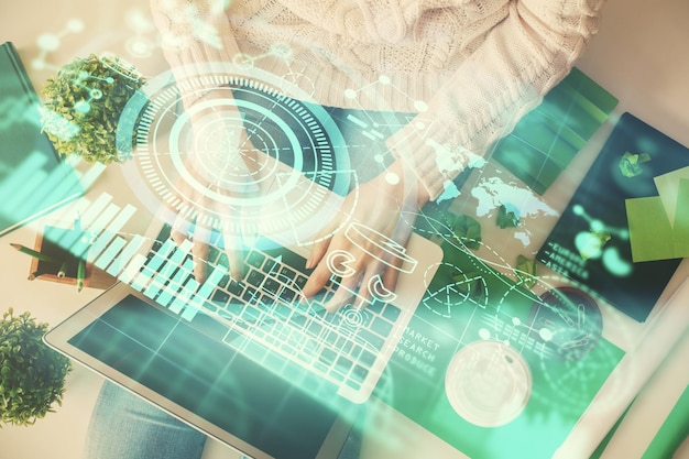 Doble exposición de manos de mujer trabajando en computadora y holograma de tema financiero dibujo concepto de negocio de vista superior