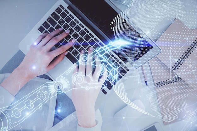 Doble exposición de manos de mujer trabajando en computadora y holograma de tema tecnológico dibujando el concepto de tecnología Top View