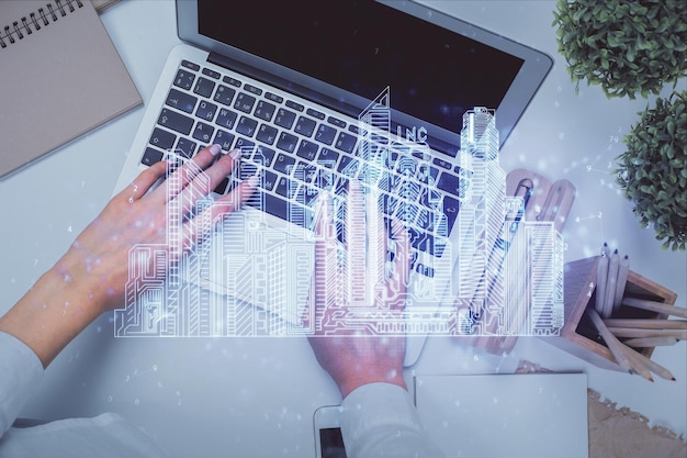 Doble exposición de manos de mujer trabajando en computadoras y construcción de edificios holograma dibujo Vista superior concepto de ciudad inteligente