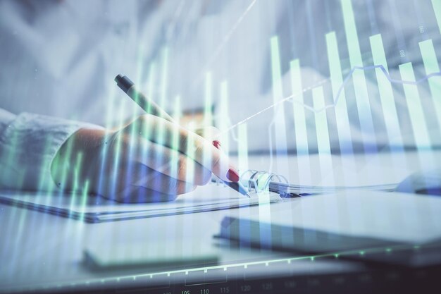 Doble exposición de las manos de las mujeres haciendo notas con holograma de gráfico de divisas Análisis conceptual del mercado de valores