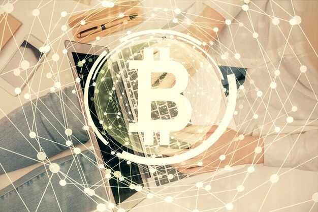 Doble exposición de manos de mujeres trabajando en computadora y dibujo holográfico de tema blockchain Top View concepto de criptomoneda bitcoin