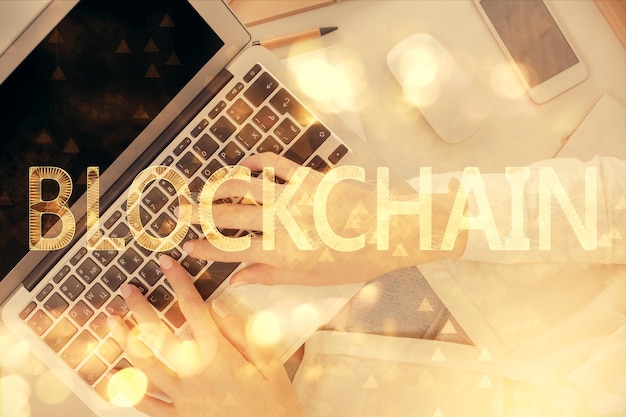 Doble exposición de manos de mujeres trabajando en computadora y dibujo holográfico de tema blockchain Top View concepto de criptomoneda bitcoin