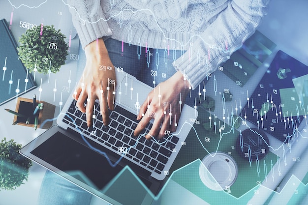 Doble exposición de manos de mujeres trabajando en computadora y dibujo de hologramas de gráficos de divisas Vista superior Concepto de análisis financiero