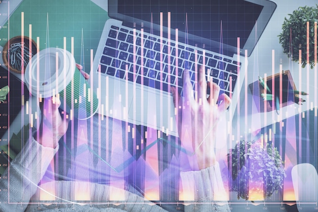 Doble exposición de manos de mujeres trabajando en computadora y dibujo de hologramas de gráficos de divisas Vista superior Concepto de análisis financiero