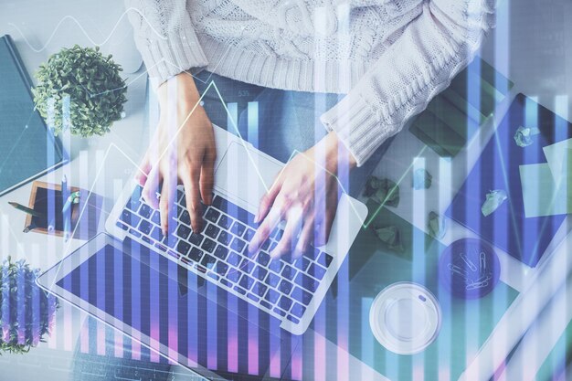 Doble exposición de manos de mujeres trabajando en computadora y dibujo de hologramas de gráficos de divisas Vista superior Concepto de análisis financiero
