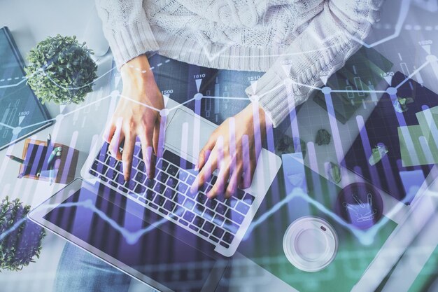 Doble exposición de manos de mujeres trabajando en computadora y dibujo de hologramas de gráficos de divisas Vista superior Concepto de análisis financiero