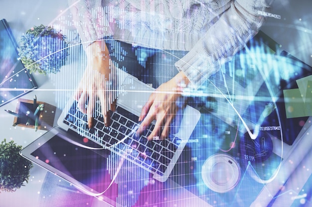 Doble exposición de manos de mujeres trabajando en computadora y dibujo de hologramas de temas financieros Top View Concepto de negocio