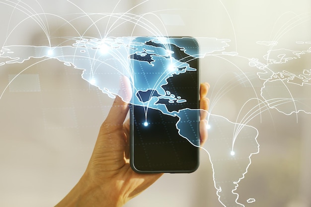Doble exposición del mapa del mundo digital abstracto con conexiones y mano con teléfono celular en el concepto de big data y blockchain de fondo